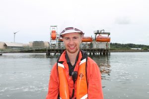 Josh smiles at the camera, with the NMCI's jetty in the background.