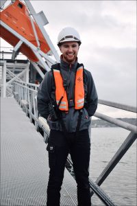 Instructor Josh, stands on the Jetty, with the freefall lifeboat behind him.